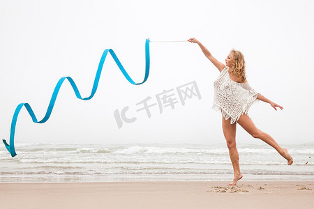 体操女子在沙滩上用丝带跳舞