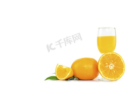 在玻璃杯中鲜榨橙汁，在白色背景上装饰着柑橘类水果和橙叶，并带有复制空间。