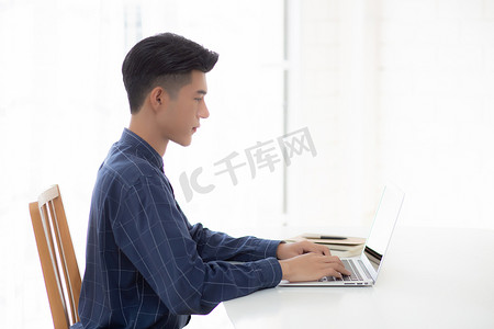 年轻商人在家工作，办公桌上放着笔记本电脑，自由职业男性坐在家里使用笔记本进行交流并在桌上放松，创业企业家，新常态。