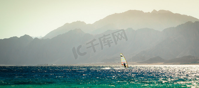 快地摄影照片_一位冲浪者在岩石的背景下在红海中骑行