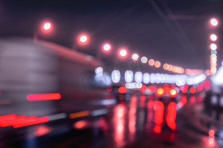 移动的汽车和灯笼的模糊灯光反射在夜城潮湿的沥青上。