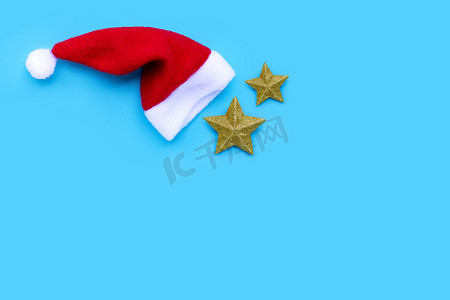 钟表金色摄影照片_蓝色背景上有金色星星的圣诞老人帽子。