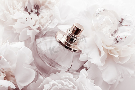 别致的香水瓶作为牡丹花背景下的奢华香水产品、香水广告和美容品牌