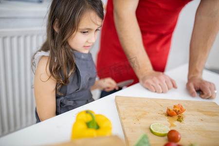 小女孩和她父亲在砧板上切蔬菜