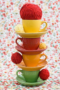 红花背景上的四个彩色杯子和毛线球