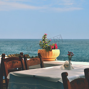 希腊小酒馆和大海中的一张有盖桌子。