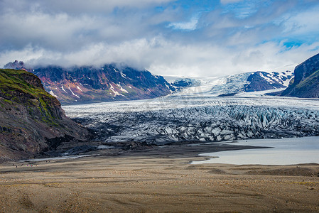 行走的力量摄影照片_Skaftafellsjokull 冰川和游客的全景，在冰岛南部的 Skaftafell 附近漫步，夏天