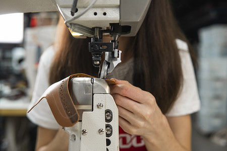 皮革车间的缝纫机在用手处理鞋子的皮革细节。