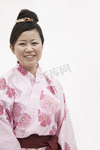 身穿粉红色日本和服的年轻微笑女子肖像，摄影棚拍摄