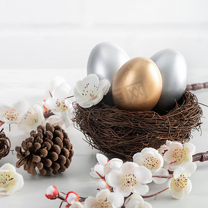关闭在巢的金黄和银色复活节彩蛋与白色梅花。