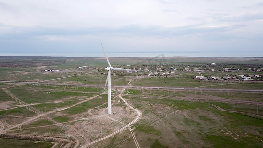 哈萨克斯坦国摄影照片_风车矗立在绿色的田野中央。
