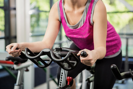 动感摄影照片_在动感单车课上骑健身车锻炼的女性