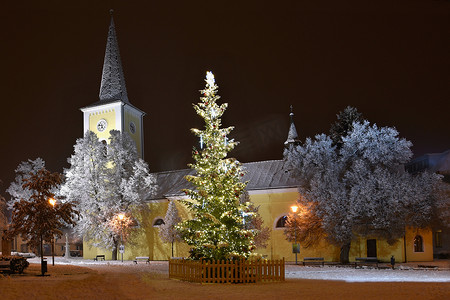 美丽的夜晚冬天照片与教堂和雪的圣诞树。