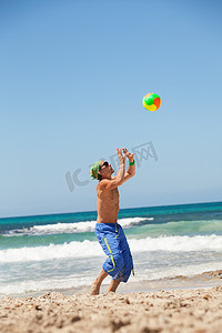 排球招新摄影照片_有魅力的年轻人在沙滩上打排球