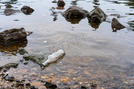 水在自然界的循环摄影照片_一个玻璃瓶在河里当垃圾。