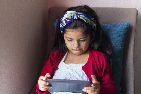 坐着的小女孩摄影照片_坐着的小女孩正在家里玩她的平板电脑