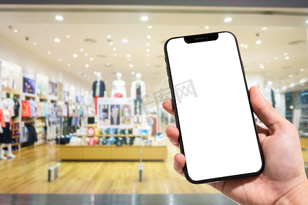 手机联系人摄影照片_女性在商场和服装店背景模糊中使用智能手机的特写模糊图像。