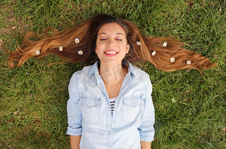 美插摄影照片_可爱的女孩梦见躺在草地上，头发上插着雏菊花