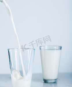 世界食物日摄影照片_世界牛奶日，倒入大理石桌上的玻璃杯中
