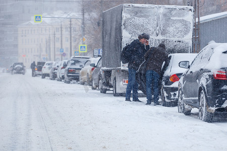 俄罗斯图拉 — 2020年2月13日：白天暴风雪期间，两名男子站在停在城市路边的汽车附近