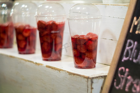 货架上展示的塑料玻璃中的草莓和糖浆，准备按客户订单制作成冰沙
