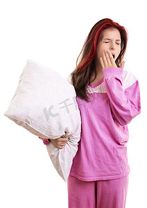 穿着睡衣的疲惫的小女孩拿着枕头打哈欠