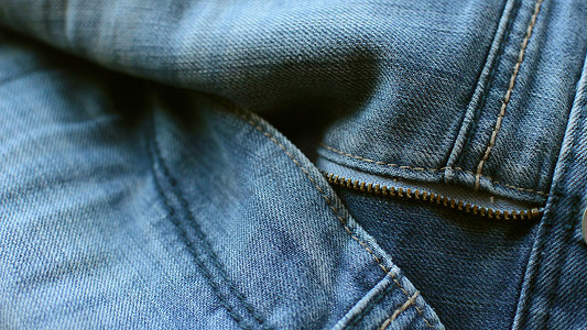 关闭蓝色牛仔裤的细节，纹理背景