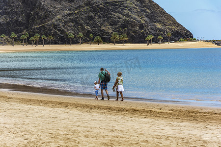 一个男人带着一个女人和一个孩子沿着荒凉的海滩 ne