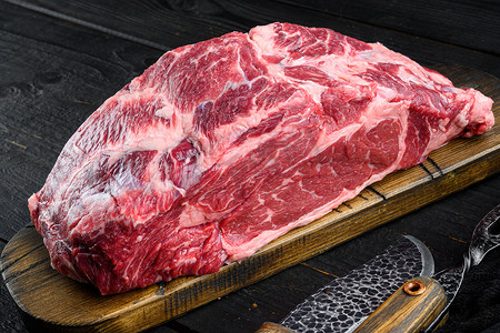 生牛肉肉食品的有机选择，肋眼切，木切板，黑色木质背景