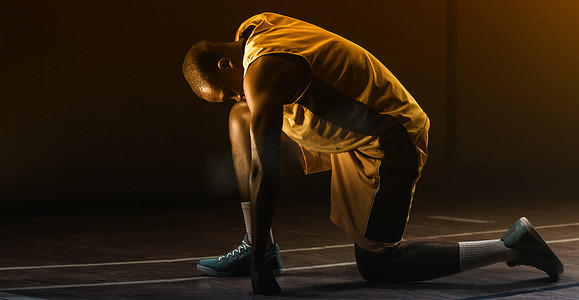 篮球运动员准备用膝盖在地板上比赛并低下头