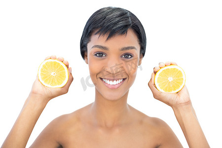 摄影师摄影照片_高兴的黑发女人拿着两半橙子
