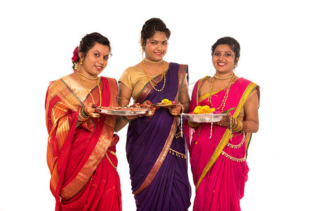 庆祝拉花摄影照片_印度传统女孩手持 diya 和花 thali 的肖像，庆祝 Diwali 或 deepavali 的姐妹们在节日期间手持油灯，背景为白色