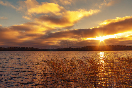 日落时分，太阳光线穿过湖面上方的云层。