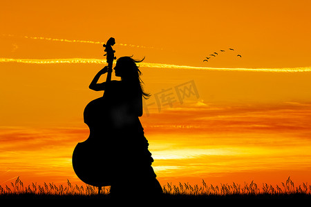大提琴摄影照片_女人在日落时拉大提琴