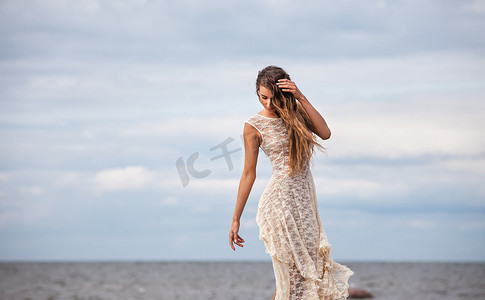 穿着半透明裙子的女孩背对着大海