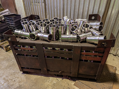 闪闪发亮的钢制零件溢出工厂地板上的大型联运钢制集装箱箱
