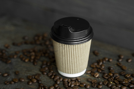 咖啡与早餐摄影照片_纸杯咖啡与木桌背景上的烤咖啡豆。