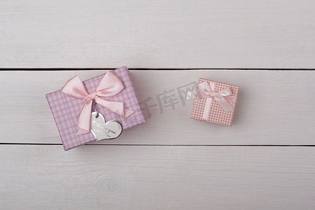 白色木桌上有两个带蝴蝶结的粉红色礼物。