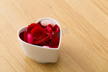 红色花瓣碎片摄影照片_在心脏碗的玫瑰花瓣