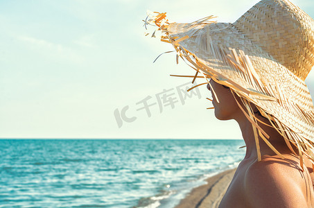 s 海浪背景中戴草帽的年轻女孩