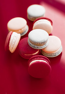 咖啡甜点摄影照片_酒红色背景的法式马卡龙、巴黎别致的咖啡甜点、甜食和豪华糖果品牌的蛋糕马卡龙、假日背景设计