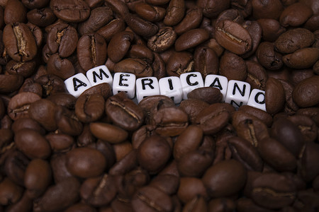 靠近用白色小方块写的 AMERICANO 字样的新鲜烘焙咖啡豆的特写。