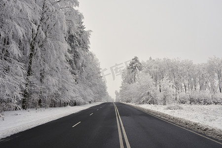 有积雪的风景的空的路。