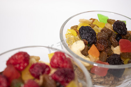 muesli 甜点配酸奶和蜜饯或干果，顶部有覆盆子，玻璃杯隔离在白色背景上。