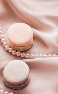 广告马摄影照片_丝绸背景上的甜马卡龙和珍珠首饰、巴黎别致的珠宝、法式甜点食品和豪华糖果品牌的蛋糕马卡龙、节日礼物