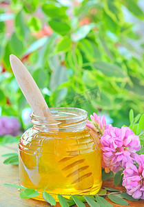 装满蜂蜜的玻璃罐和粘着粉红色和白色相思花的蜂蜜