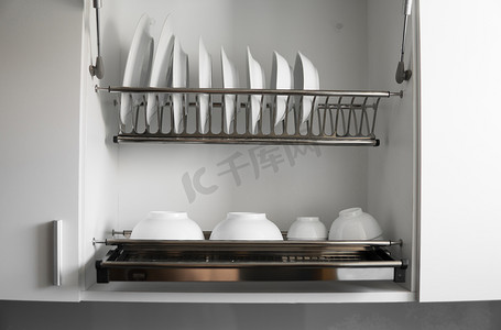 洗碗摄影照片_带有大而漂亮的白色干净盘子的洗碗机金属架。