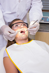 牙医椅摄影照片_儿科牙医在牙医椅上检查病人的牙齿
