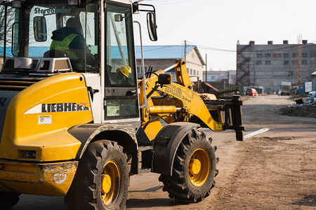 黄色反摄影照片_LUTSK, UKRAINE - May 10, 2020：黄色轮式装载机挖掘机在锯木厂工作。