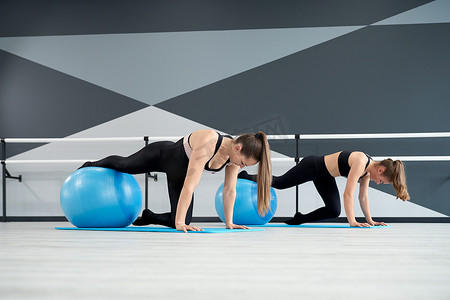健身球摄影照片_女性使用健身球练习平板支撑姿势。